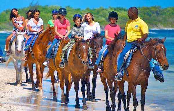 Horseback riding on the beach Jamaica - group of riders on horses along Caribbean shore