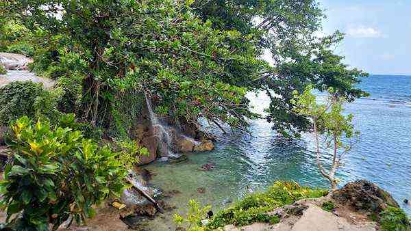 Little Dunn's River Jamaica - hidden waterfall with Jamaican flag people swimming tropical
